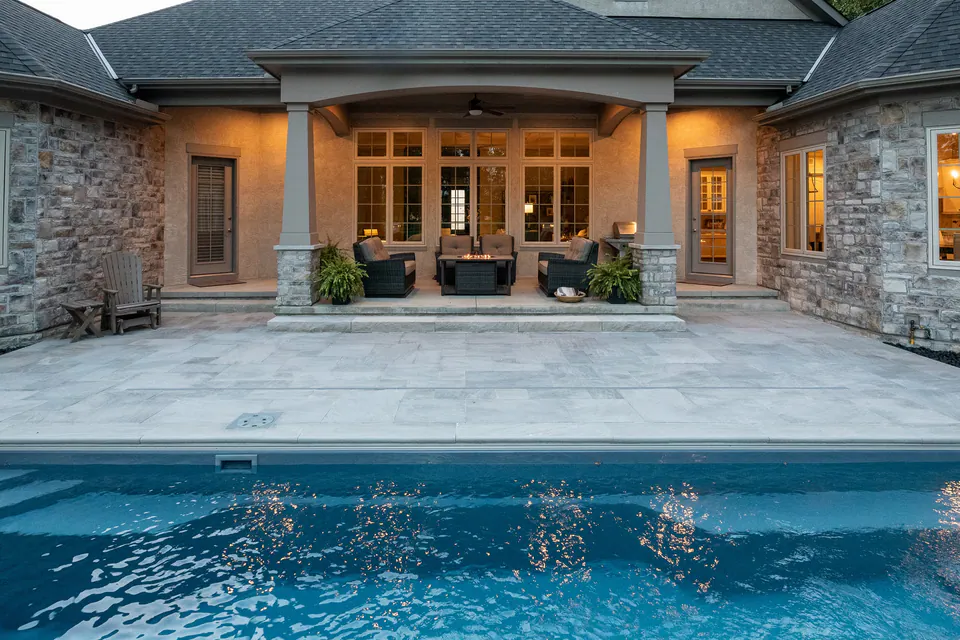 Bluestone pool terrace running between the pool and the covered back porch of a stone house